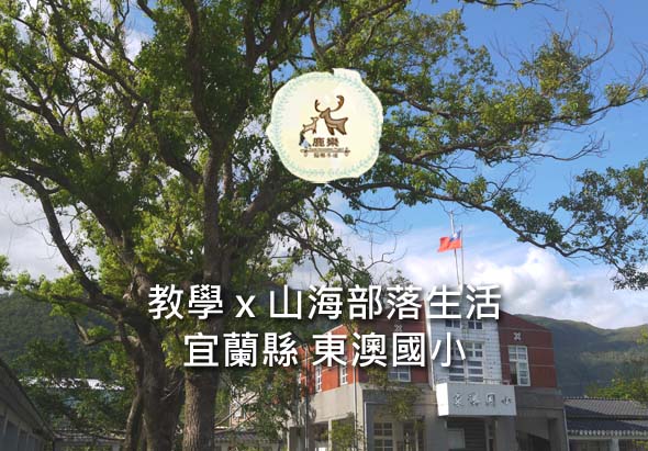 宜蘭縣東澳國小校舍前，高大老樹下豎立著「教學×山海部落生活」的活動標誌，背景為紅磚校舍和飄揚的國旗，呈現山區原住民部落學校的特色。