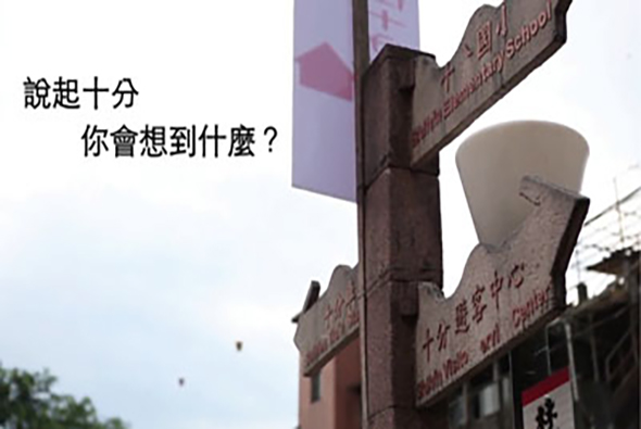 街道上的十字路口指示牌，牌面寫著中文字，左側有文字「說起十分 你會想到什麼？」提示觀看者思考。背景為建築物和天空。