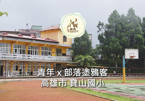 高雄市寶山國小校園，黃色建築物前方紅土籃球場，右側籃球架，校舍牆面寫有「青年×部落涯獵客」文字，上方懸掛學校校徽。
