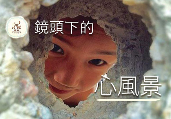 一個孩童的臉部透過石縫隙露出，展現溫暖笑容。圖片標題「鏡頭下的心風景」，暗示從攝影視角發現人性美好。左上角有藝術創作相關logo。