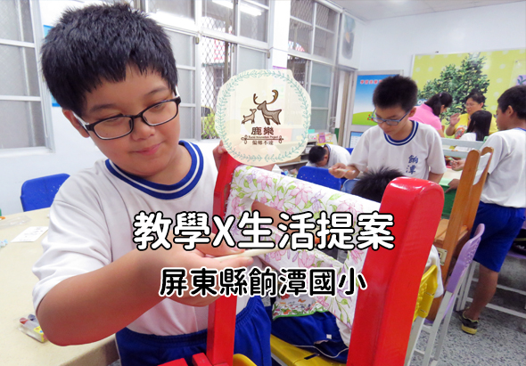 屏東縣飼灣國小學生在教室內進行教學與生活提案活動，男童戴著眼鏡專注地堆疊紅色積木，背景有其他學生參與活動，牆上貼著鹿鹿logo海報。