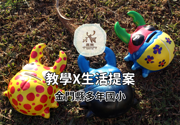 草地上放置多個彩色充氣玩具，包括黃紅相間的鹿鼻玩具和藍黃色點點圖案的球形玩具。中央白色圓形標誌寫著「鹿驛」。圖片下方繁體中文文字寫著「教學×生活提案 金門縣多年國小」，展示教育與生活結合的主題。