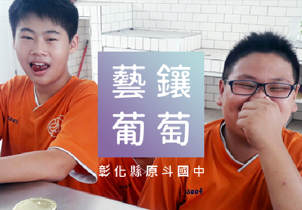 彰化縣原斗國中兩名學生穿著橙色制服，在教室內開心地展示「藝鑄葡萄」宣傳海報。海報以紫藍色背景搭配白色繁體字，介紹學校的特色課程或活動項目。