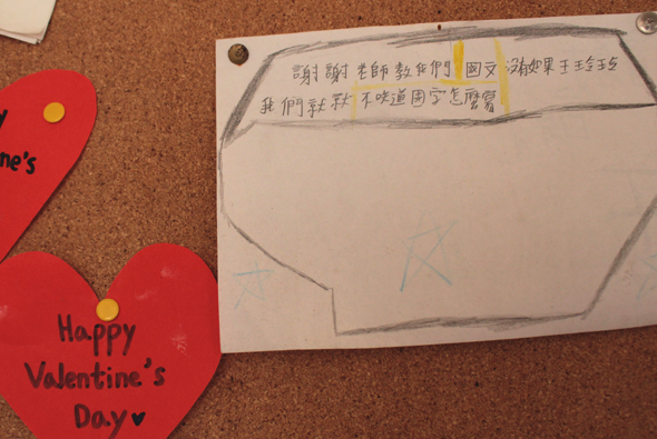 軟木布告欄上放著兩個紅色愛心卡片，左下角寫著「Happy Valentine's Day♥」。上方是一張手寫的信封式卡片，內容用中文寫著感謝詞和祝福語，表達對老師的感謝之意。