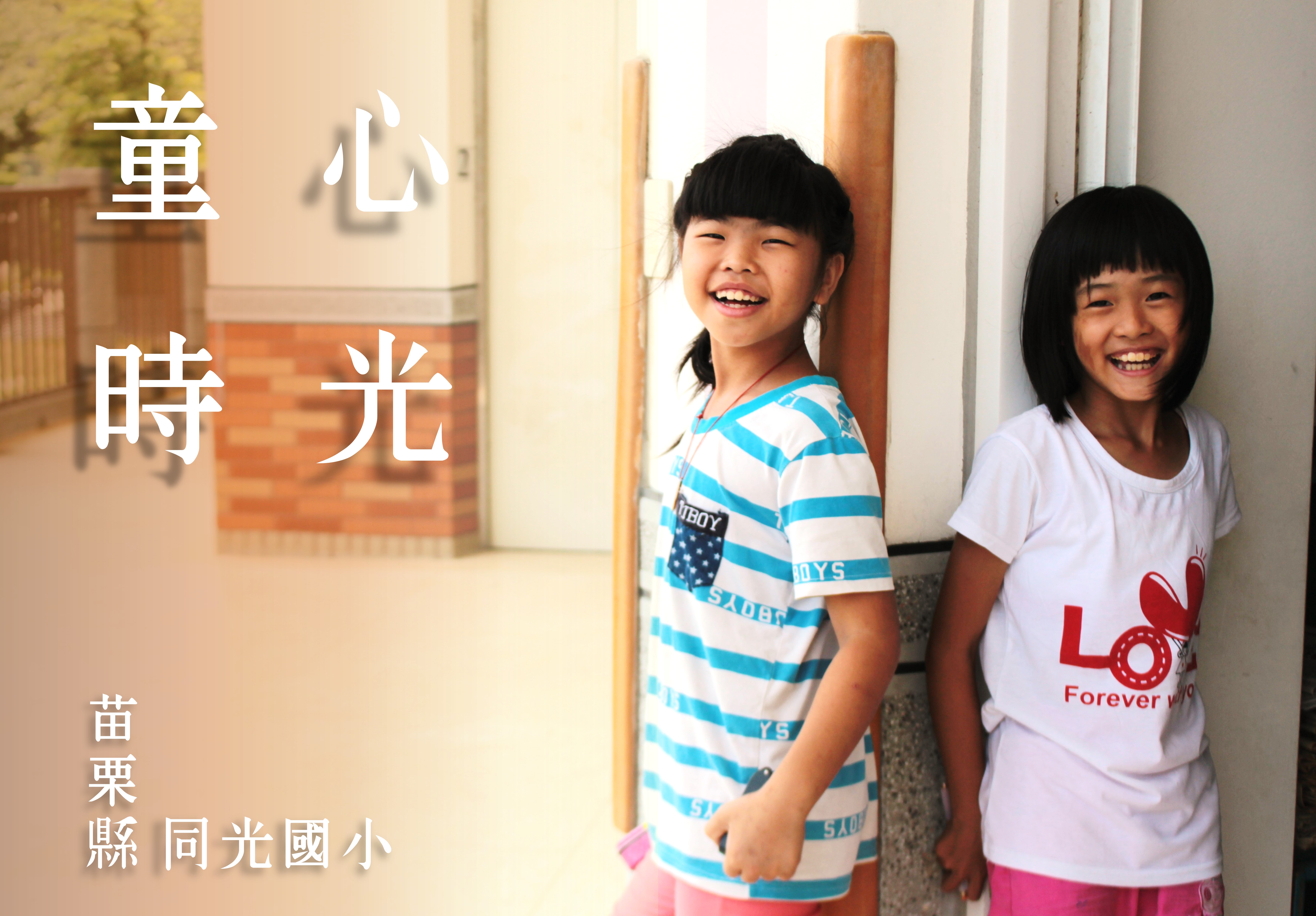 兩位笑容燦爛的小女孩站在室內走廊，穿著藍白條紋和白色T恤。左側有中文文字「童心時光」，下方標註「苗栗縣同光國小」。溫暖的自然光線灑入，營造溫馨的校園氛圍。