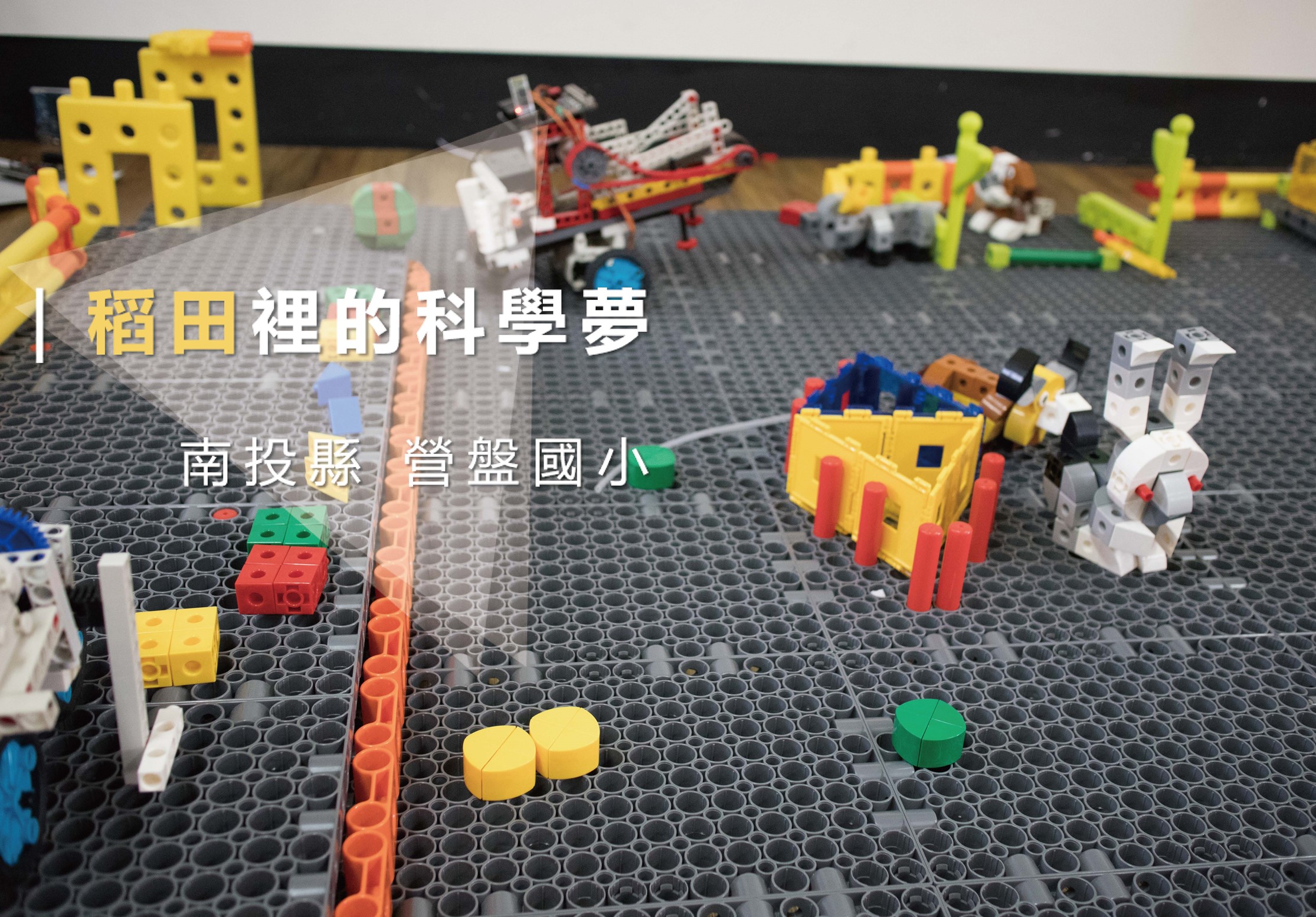 樂高科學夢展示場景，黑色基板上擺放各色樂高積木搭建的建築、機械裝置、黃綠色結構和白色機器人等作品。左上方黃色標題文字「稻田裡的科學夢」，下方標註「南投縣營盤國小」，展現學生的科技創意作品。