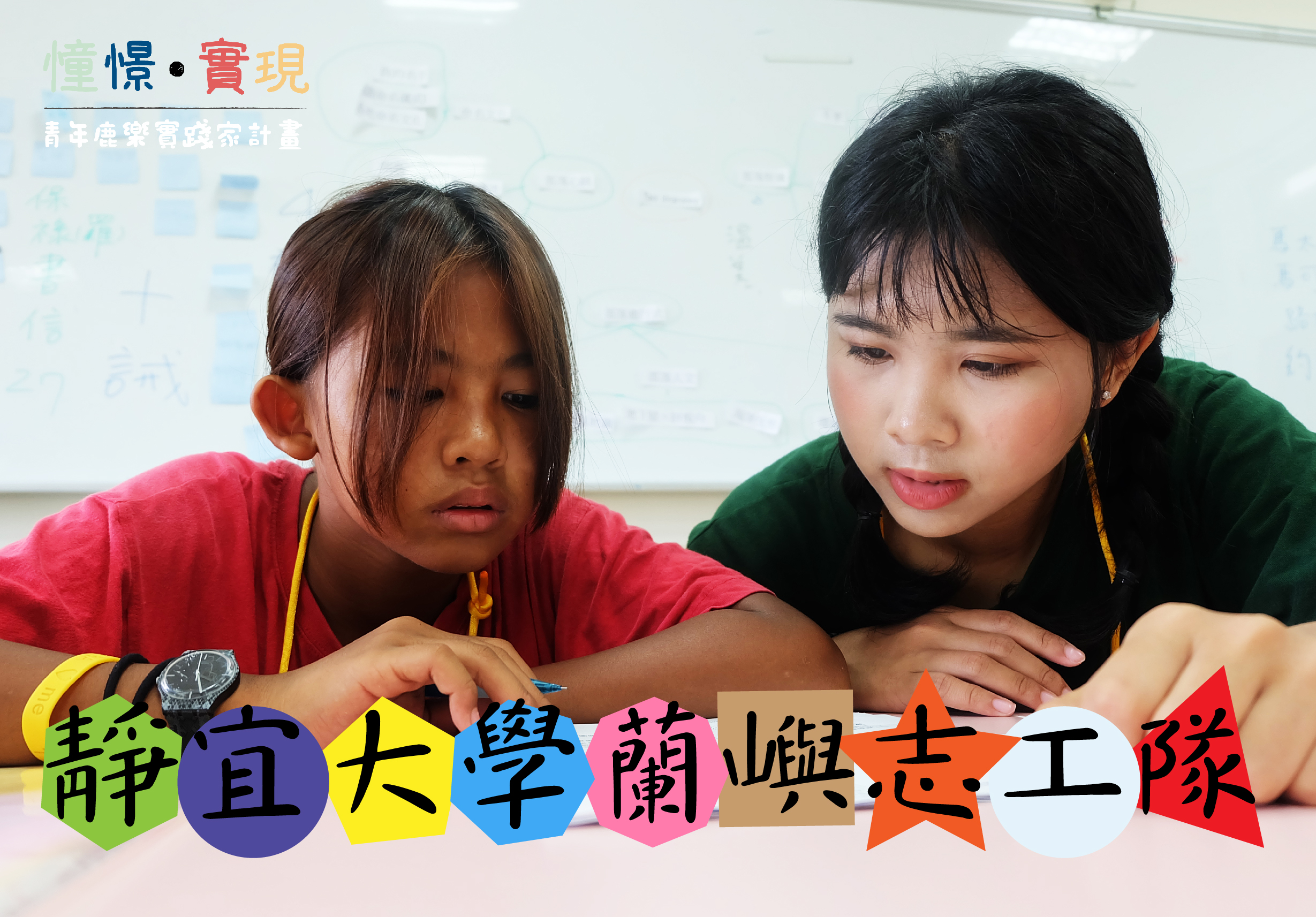 兩位年輕女性在教室內進行STEAM教育活動，一位穿紅衣、一位穿綠衣，正專注地操作電子零件。背景為白板，下方有彩色字卡標示「靜自大學蘭與志工隊」，呈現科技教育的互動學習場景。