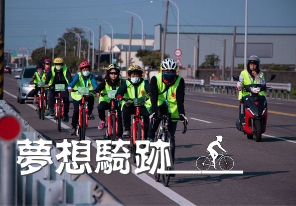 一群穿著螢光黃綠背心和安全帽的騎士在橋上騎紅色自行車進行團體騎行活動。畫面左下角有「夢想騎跡」文字和自行車圖標，右側有紅白相間的警示標誌。背景可見工業設施和晴朗天空。
