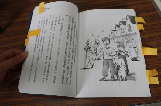 開啟的書籍頁面，左頁為繁體中文文字內容，右頁為黑白插圖，描繪一個家庭場景，包括成年人和兒童站在房屋前。書頁用黃色書籤標記。