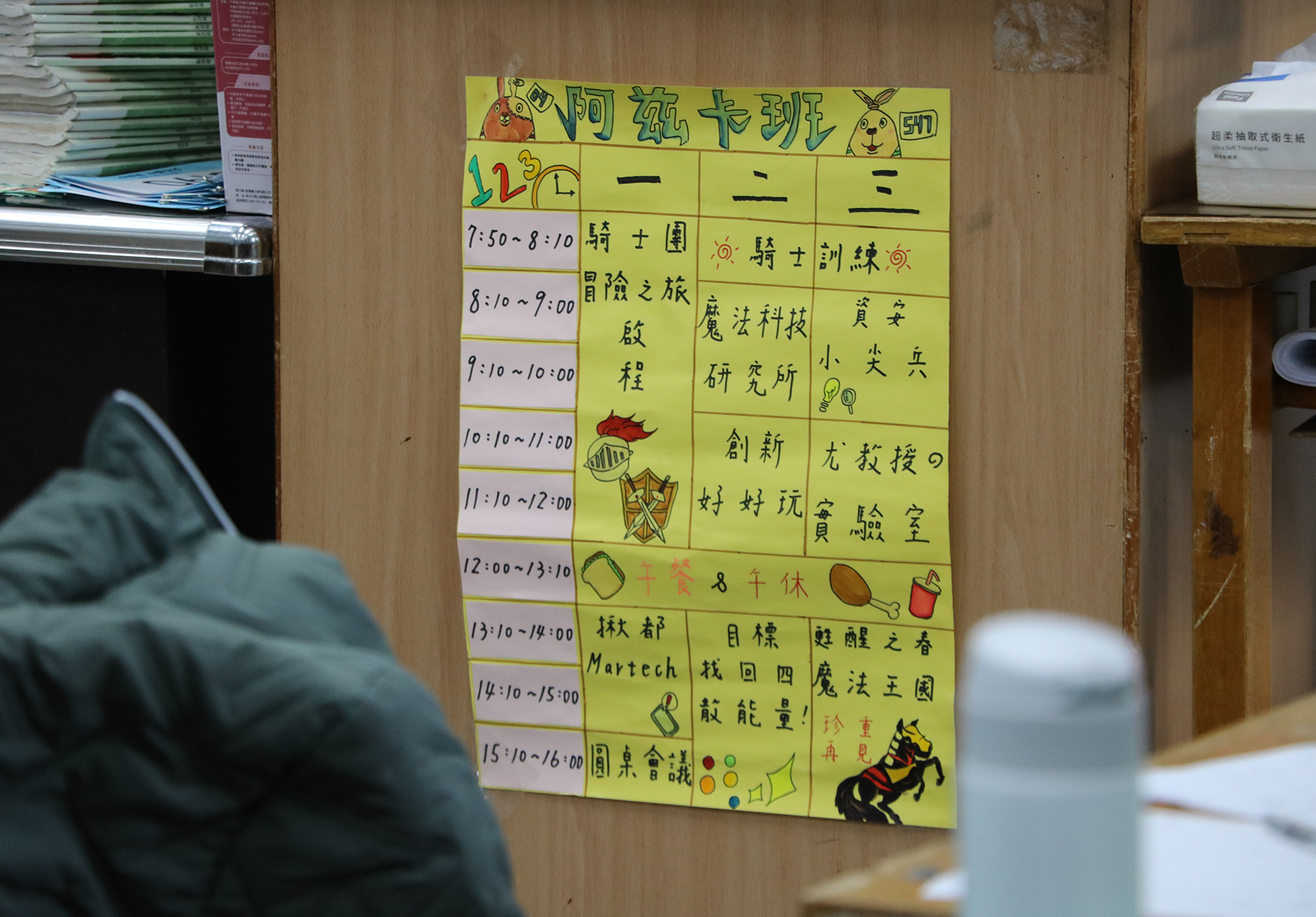 阿純卡班週一至週三課程表，黃色背景，列出7:50至16:00各時段的課程安排，包括讀書會、冒險之旅、魔法科技、創新對對玩、林郁Martech、圓桌會議等活動，搭配卡通圖案裝飾。