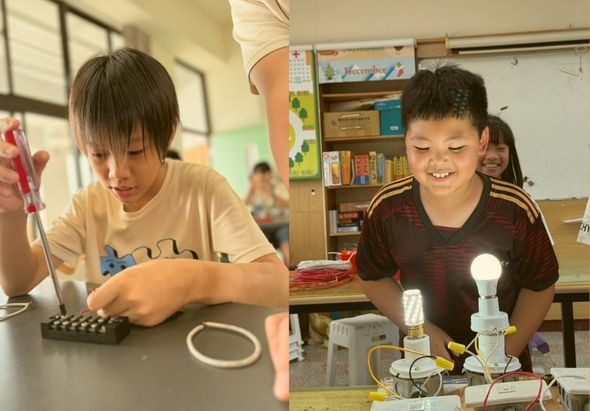 兩名小學生在教室進行科學實驗。左邊男童操作電子元件裝置，右邊男童面帶笑容，身旁擺放著LED燈泡和電路組件。背景可見教室書架和其他學生，展現動手學習的教育情景。