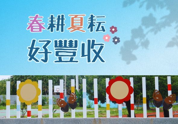 春耕夏轉好豐收主題海報。上方藍色天空背景配粉紅、灰色齒輪裝飾。下方為白色柵欄圍籬前，掛著黃色和紅色大圓形裝飾，以及棕色稻草人玩偶，象徵農業豐收的主題設計。