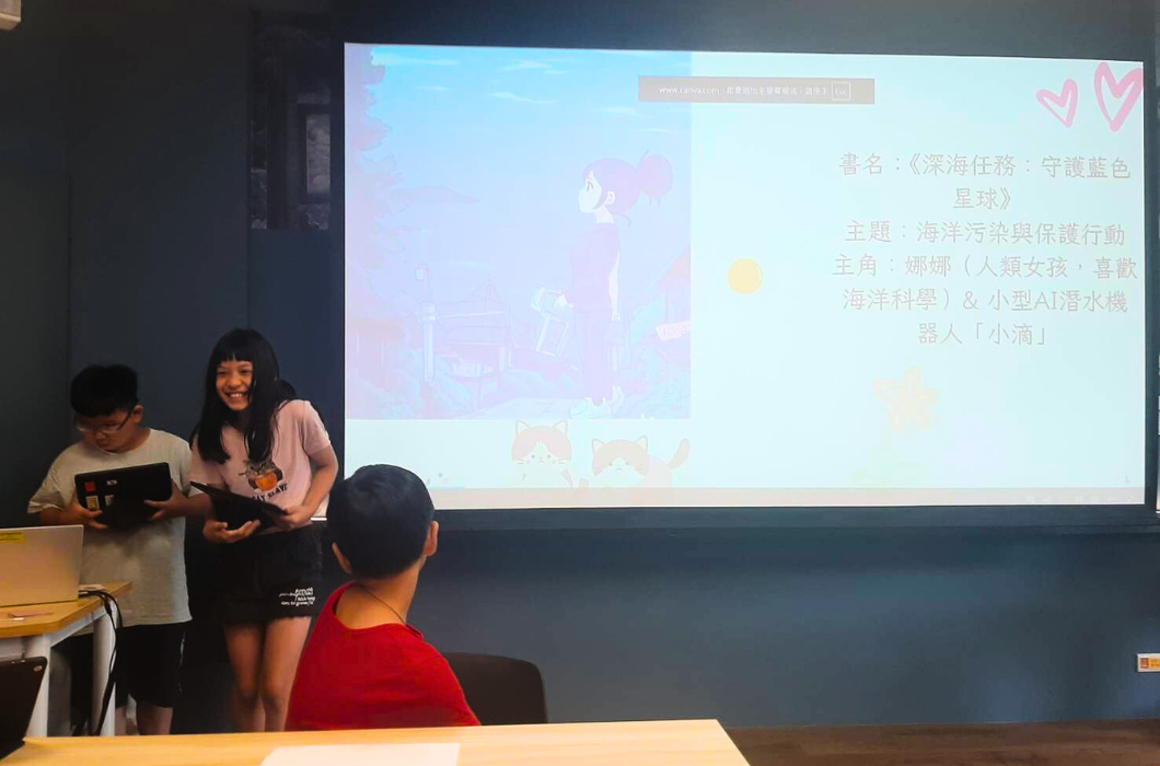課堂教學現場，一位女講師站在投影幕前，向學生介紹《深海任務：守護藍色星球》繪本。幕上展示書籍內容、主角姐妹與小型AI清水機器人的介紹，主題涵蓋海洋污染與保護行動。前方學生認真聆聽與互動。
