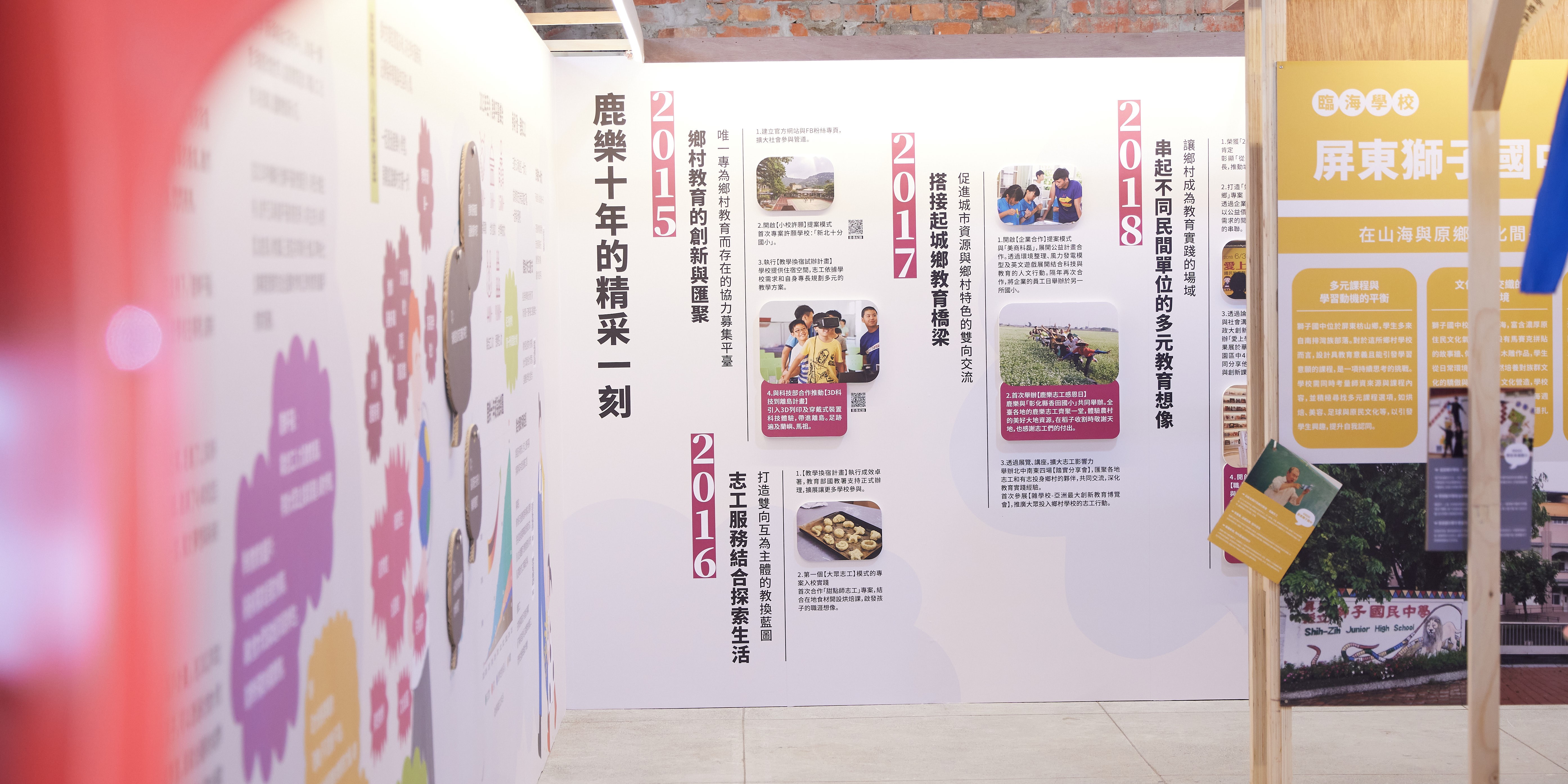 室內展示牆面展出多張宣傳海報，標題包括「鹿樂十年的精彩一刻」、「2015鄉村教育創新與匯聚」、「2017搭接起城鄉教育橋染」及「2018屏東樹子國」等。海報搭配照片、文字說明及統計數據，呈現教育推廣與鄉村發展的年度成果與計畫內容。