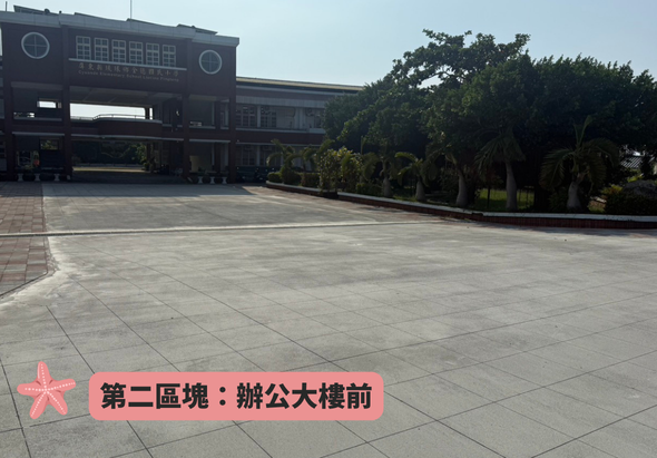 辦公大樓前的寬敞廣場，鋪設灰色地磚，左側有紅色五角星標誌標示「第二區塊：辦公大樓前」，背景為現代建築物和綠化樹木，天色晴朗。