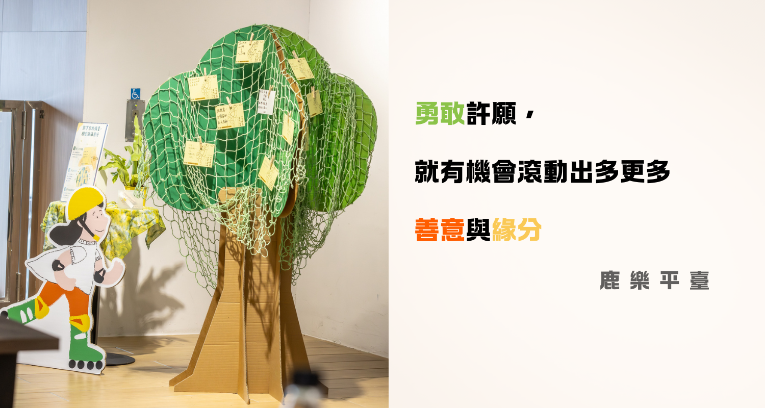 畫面左側是一棵由紙箱與綠色防護網製成的立體「許願樹」，樹上夾著許多黃色許願卡，樹旁有一位黃色安全帽卡通人物立牌；右側搭配金句：「勇敢許願，就有機會滾動出更多更多善意與緣分。」（出處：鹿樂平台）