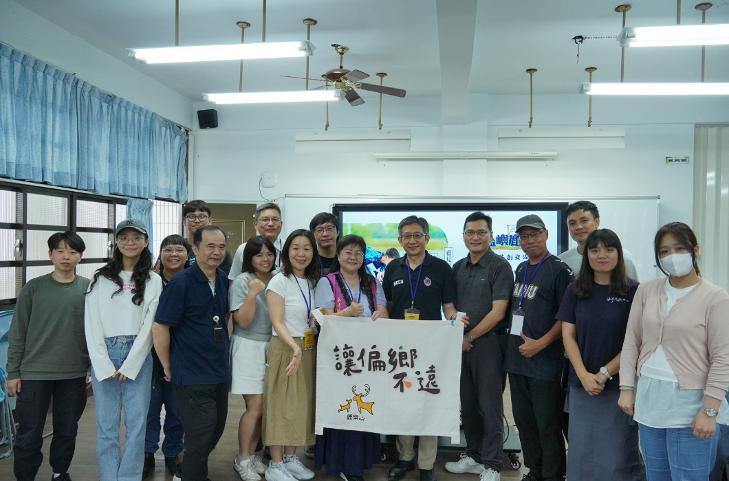 教室內多位參與者合影留念，中央展示寫有「讓偏鄉不遠」的布旗，現場氣氛溫馨熱絡。