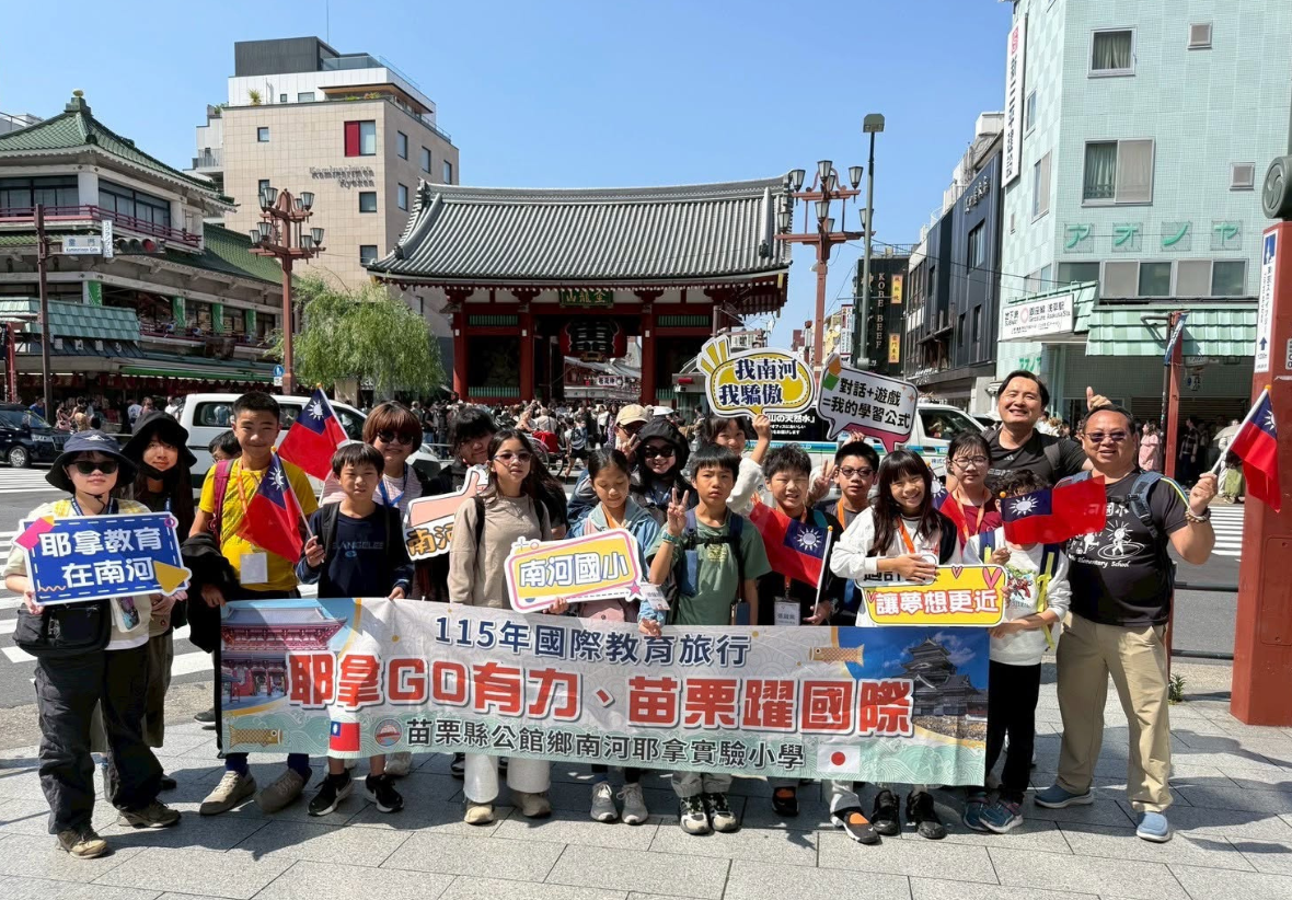 南河國小師生在雷門前合影。眾人拉著「苗栗縣公館鄉南河耶拿實驗小學、國際教育旅行」布條，手持國旗與「南河我驕傲」手牌，背景為日本淺草寺雷門。