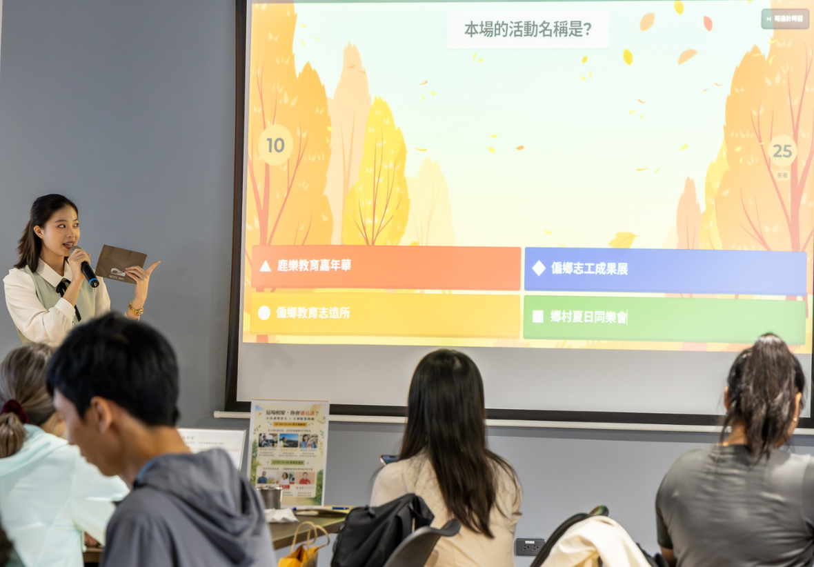 左側，一位女性主持人手持麥克風在簡報螢幕前微笑演講。