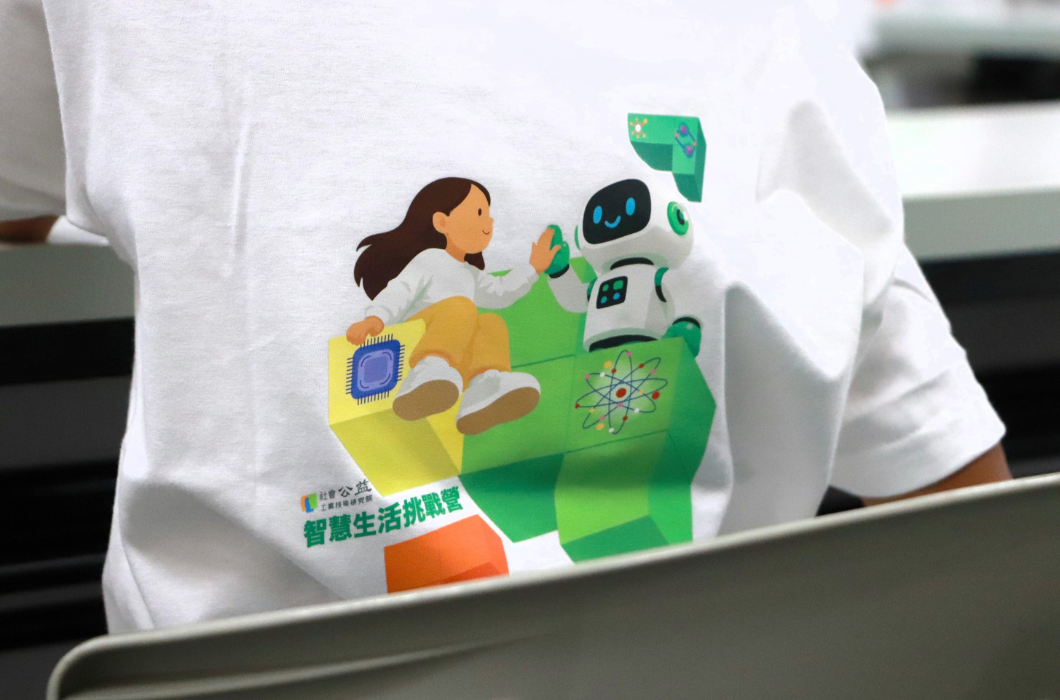 白色活動上衣印有女孩與機器人擊掌的彩色圖案，下方標示「2026智慧生活挑戰營」，象徵孩子與科技相遇。