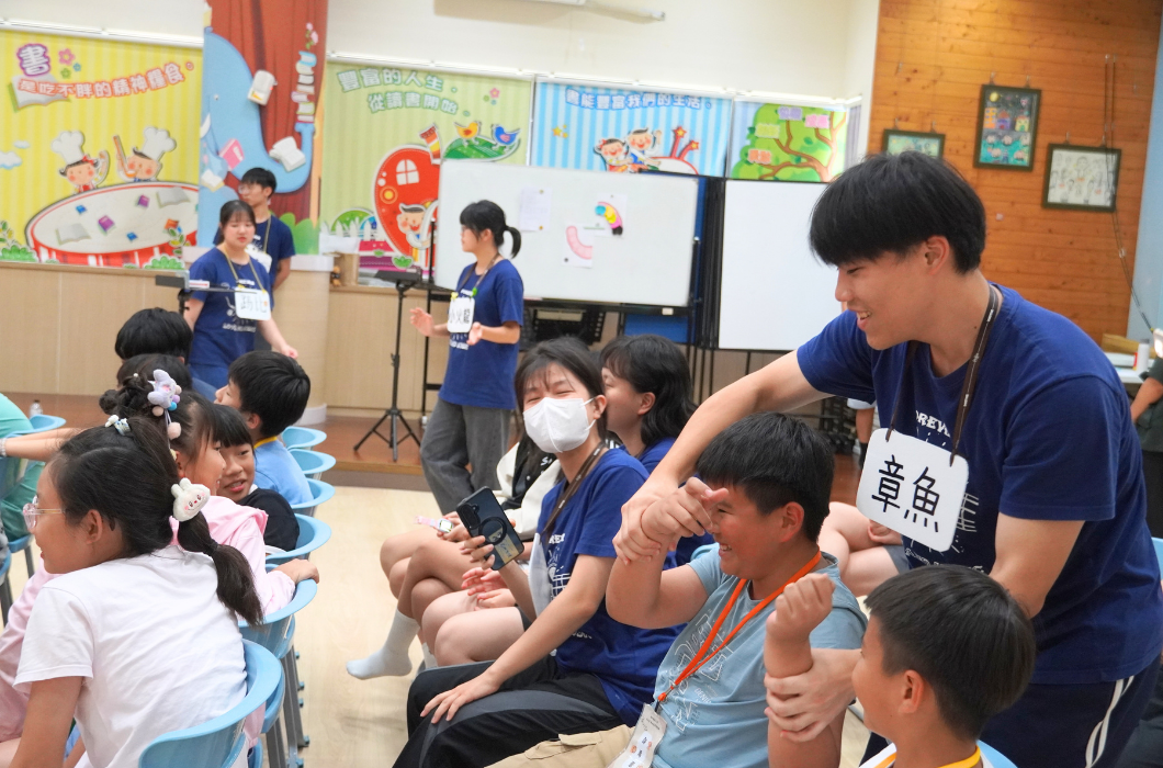 名牌為「章魚」的隊員俯身引導學童伸展手臂律動，周遭的學童與隊員皆笑逐顏開，氣氛歡樂溫馨。