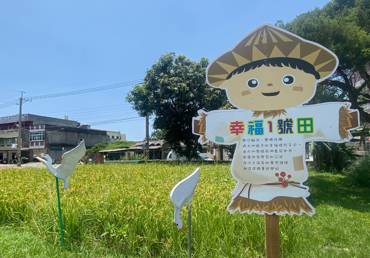 綠油油的稻田旁立著「幸福 1 號田」的可愛稻草人造型指示牌，邊緣還設有白鷺鷥造型的裝置藝術。