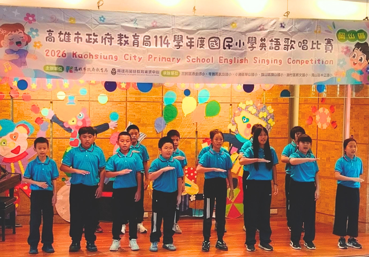 高雄市國小英語歌唱比賽現場，學生們身穿藍色制服同手同腳於舞台上排開，配合歌曲進行肢體動作與精彩合唱。