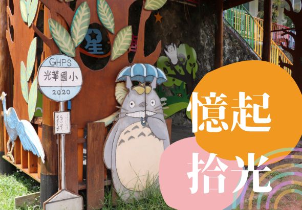 光華國小2020年校園布置，紅色木製門面上掛著龍貓卡通人物剪影、葉子裝飾及學校標誌，右側有橙色和粉紅色圓形標語寫著「意起拾光」，營造溫馨校園氛圍。