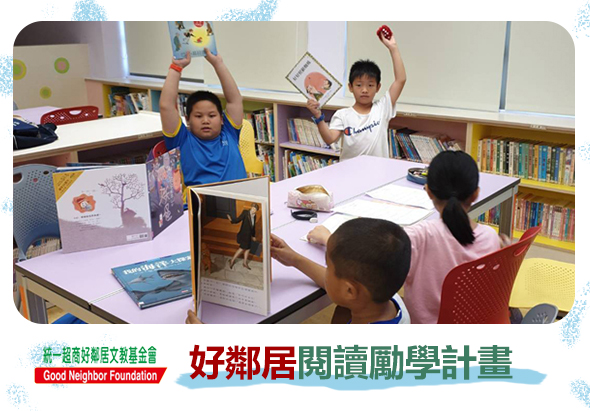 好鄰居閱讀勵學計畫活動現場。圖書館內，兒童圍坐在桌前閱讀書籍，兩名學生舉起雙手表示歡樂，展示閱讀的樂趣。背景為書架和教室環境，推廣兒童閱讀教育。