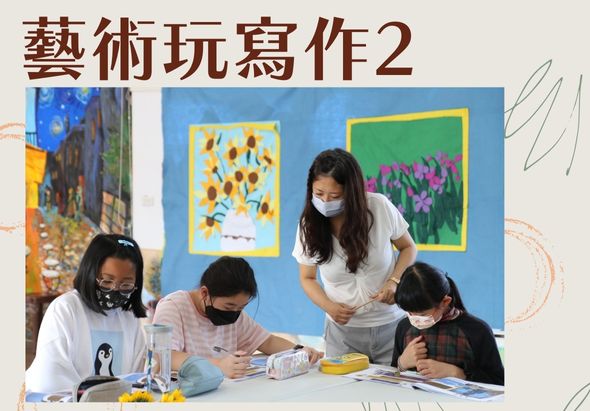 藝術玩寫作2。一名戴口罩的女性教師與三名戴口罩的學生在藍色牆壁前的桌子旁進行藝術創作活動。牆上展示向日葵和花卉畫作。桌上擺放繪畫用具和材料。