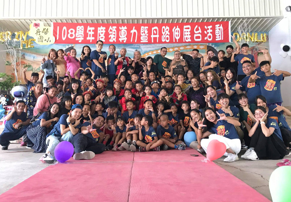108學年度領導力暨母娘文化台灣巡迴活動集合照。大批參與者穿著黑色與彩色服裝，齊聚在粉紅色舞台上。背景掛有紅色橫幅，舞台前方擺放彩色氣球。眾人歡樂地擺姿勢合照，展現活動的熱鬧氛圍。