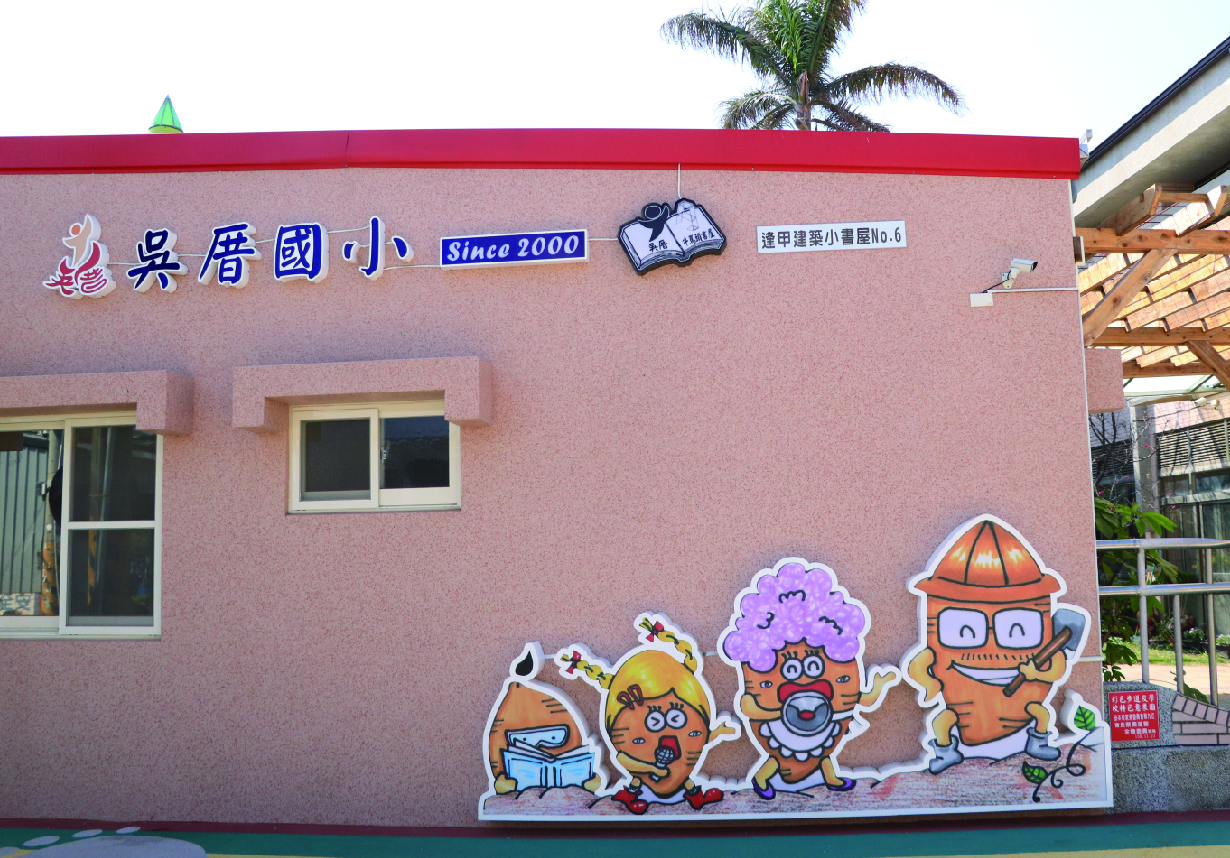 港尾國小校舍外牆，粉紅色牆面上方有校名及「Since 2000」字樣，下方裝飾著五個卡通人物角色貼圖，包括正在讀書、運動、救火員等造型，右側有木造涼亭和綠色植物。