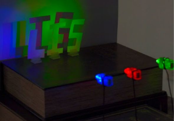 黑色木製展示台上放置發光的LED數字和字母裝飾品，展示藍色「36」、紅色「40」和綠色的文字，搭配彩色背景燈光營造科技感氛圍。