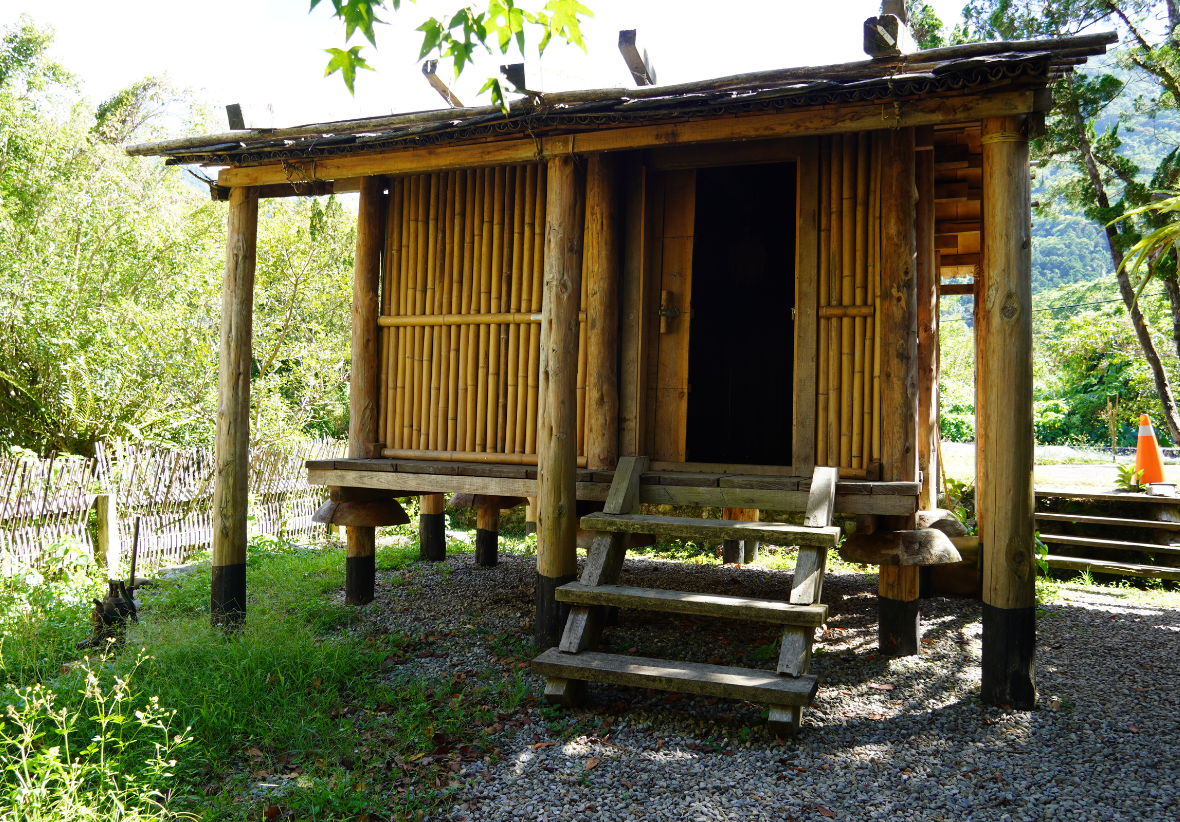 傳統木造建築，採用立柱和木板牆結構，配有木製門窗和台階。建築座落於山區，周圍被綠樹環繞，展現古樸的鄉村建築風格。